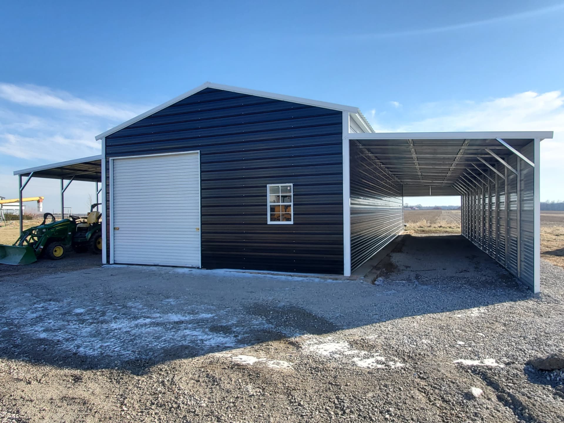 Navy Tri-State garage with white roll-up door and long lean-to carport